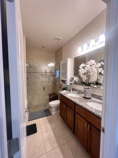 bathroom with toilet, a shower with door, tile patterned flooring, a textured ceiling, and vanity