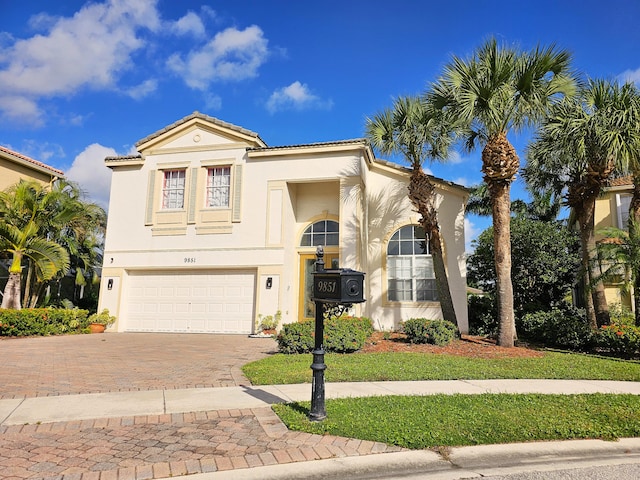 mediterranean / spanish-style house featuring decorative driveway, a tile roof, an attached garage, and stucco siding