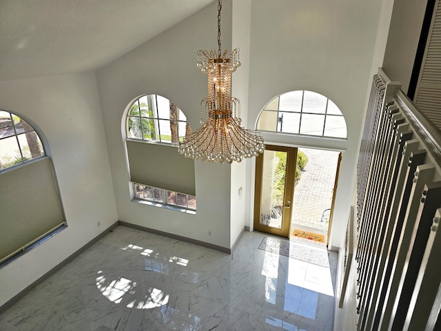 entrance foyer featuring an inviting chandelier, baseboards, marble finish floor, and high vaulted ceiling