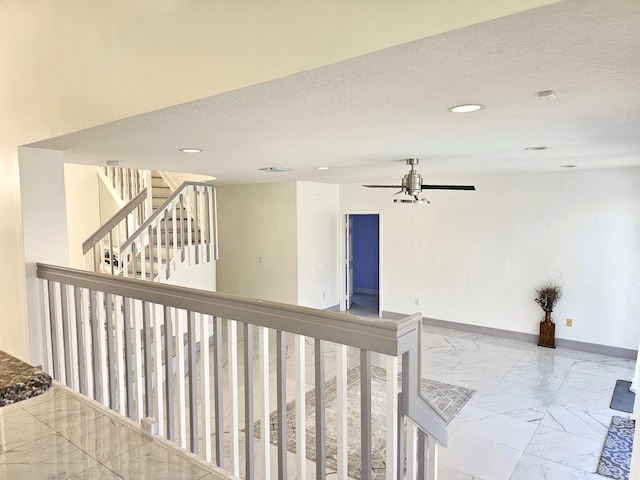 hallway with a textured ceiling, marble finish floor, recessed lighting, and baseboards