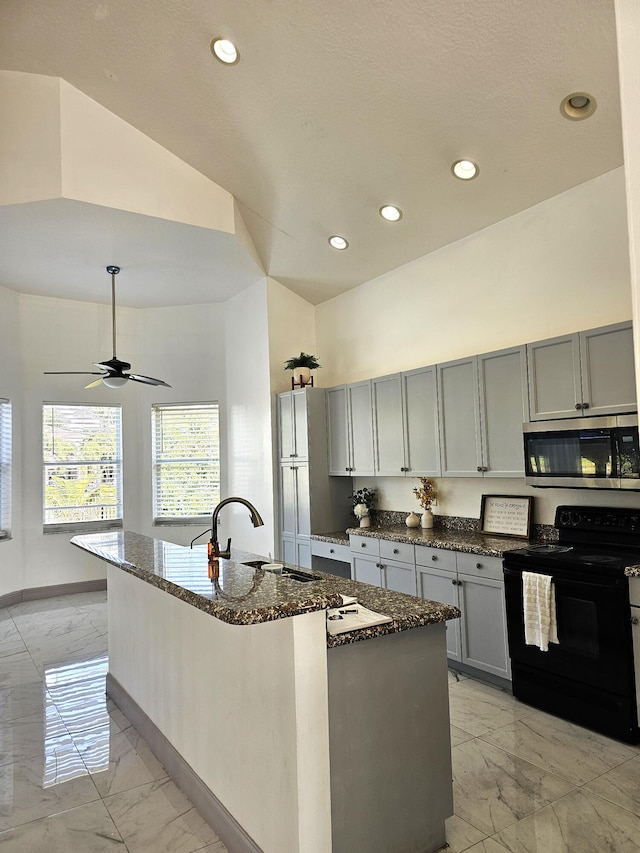 kitchen featuring marble finish floor, stainless steel microwave, black range with electric stovetop, gray cabinetry, and dark stone countertops