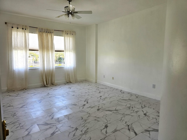 empty room with marble finish floor, baseboards, and a ceiling fan