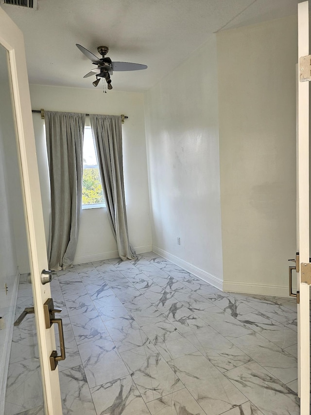 unfurnished room with a ceiling fan, marble finish floor, visible vents, and baseboards