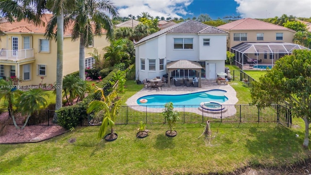 back of property featuring a fenced backyard, a pool with connected hot tub, and a lawn