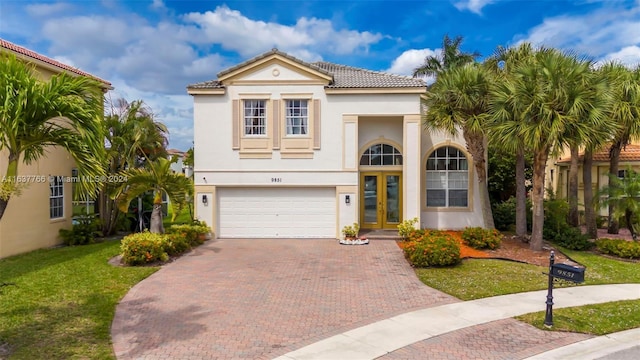 mediterranean / spanish-style house featuring a garage, french doors, decorative driveway, stucco siding, and a front yard