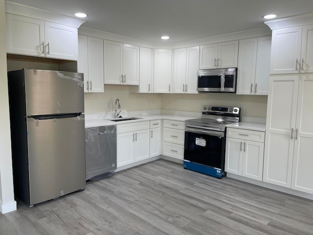 kitchen with sink, white cabinets, stainless steel appliances, and light wood-type flooring