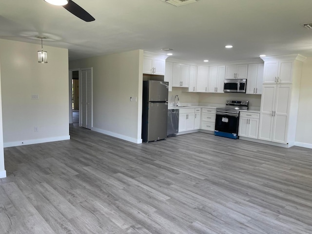 kitchen featuring pendant lighting, light hardwood / wood-style flooring, white cabinets, and stainless steel appliances