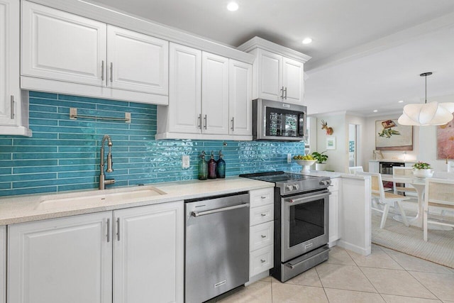 kitchen with sink, decorative light fixtures, light tile patterned floors, appliances with stainless steel finishes, and white cabinets