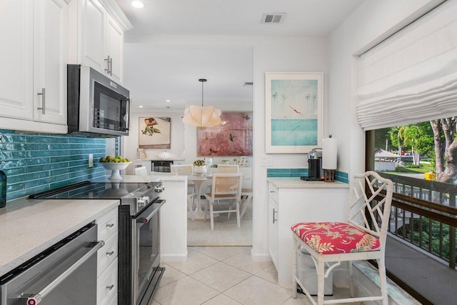 kitchen featuring tasteful backsplash, appliances with stainless steel finishes, pendant lighting, and white cabinets