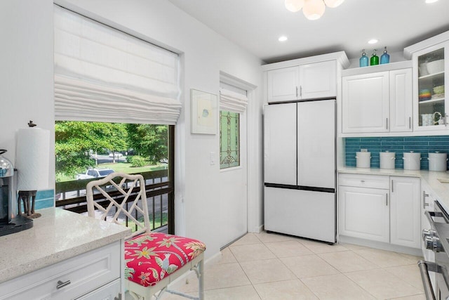 kitchen featuring light tile patterned floors, decorative backsplash, white cabinets, and white refrigerator