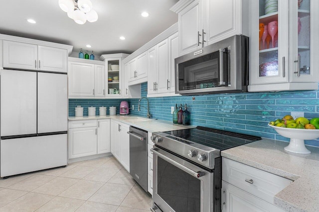 kitchen with light tile patterned flooring, appliances with stainless steel finishes, sink, white cabinets, and decorative backsplash