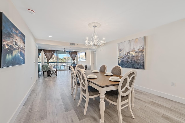 dining space with ceiling fan with notable chandelier and light hardwood / wood-style flooring