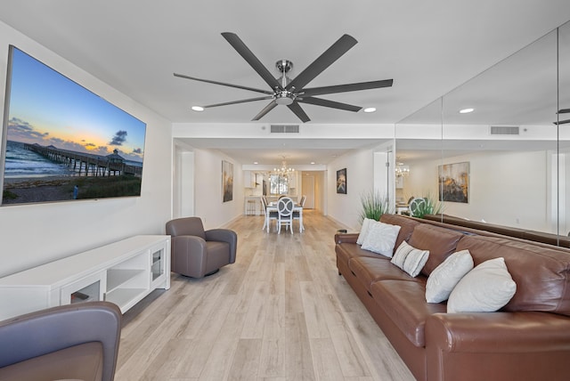 living room featuring ceiling fan with notable chandelier and light hardwood / wood-style floors