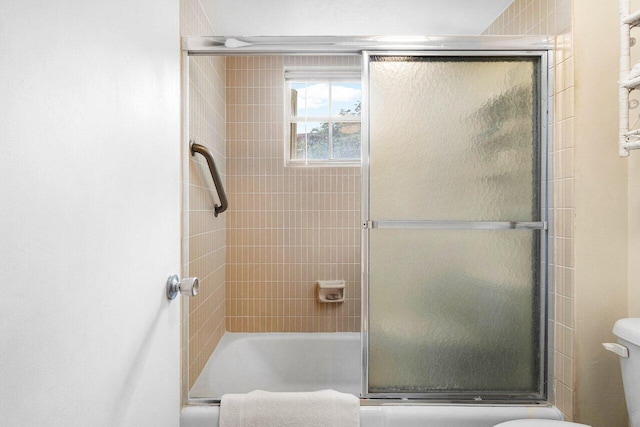 bathroom featuring bath / shower combo with glass door and toilet