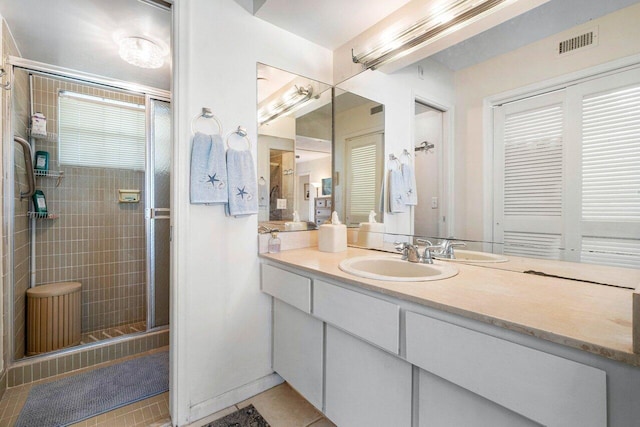 bathroom with tile patterned flooring, vanity, and walk in shower