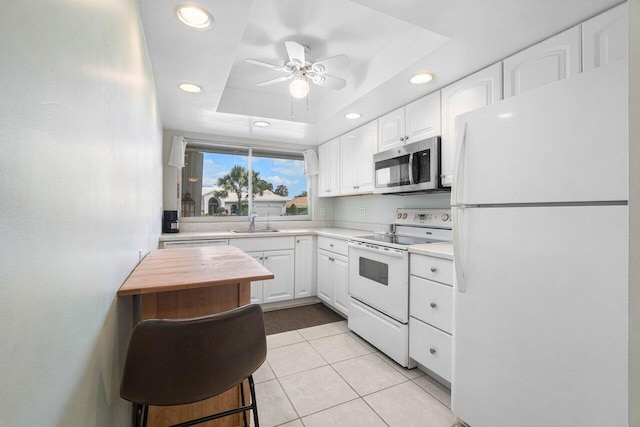 kitchen featuring range with electric cooktop, white fridge, white cabinetry, and a tray ceiling