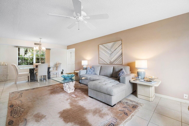 living room featuring ceiling fan with notable chandelier, light tile patterned floors, and a textured ceiling