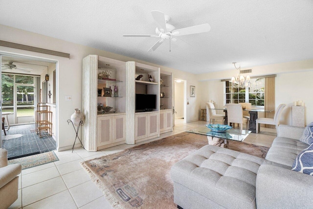 living room featuring ceiling fan with notable chandelier, plenty of natural light, light tile patterned floors, and a textured ceiling