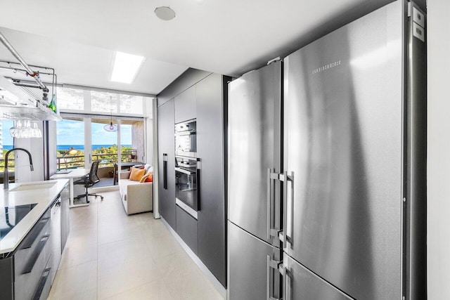 kitchen with black double oven, expansive windows, high quality fridge, and sink