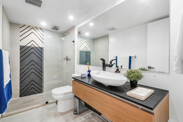 bathroom with tiled shower, vanity, and toilet