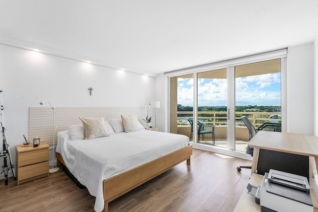 bedroom featuring expansive windows, wood-type flooring, and access to outside