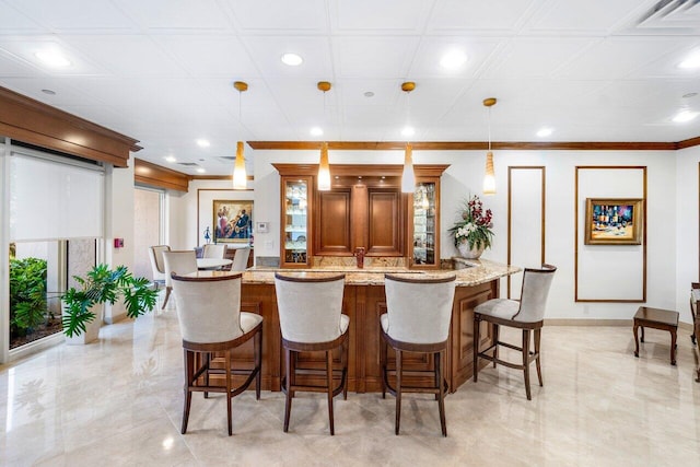 kitchen with light stone countertops, a breakfast bar, a center island, and decorative light fixtures