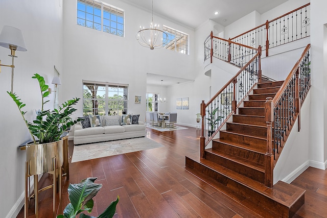 foyer entrance featuring an inviting chandelier, dark wood-type flooring, and a towering ceiling