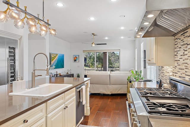 kitchen with appliances with stainless steel finishes, cream cabinetry, backsplash, sink, and custom exhaust hood