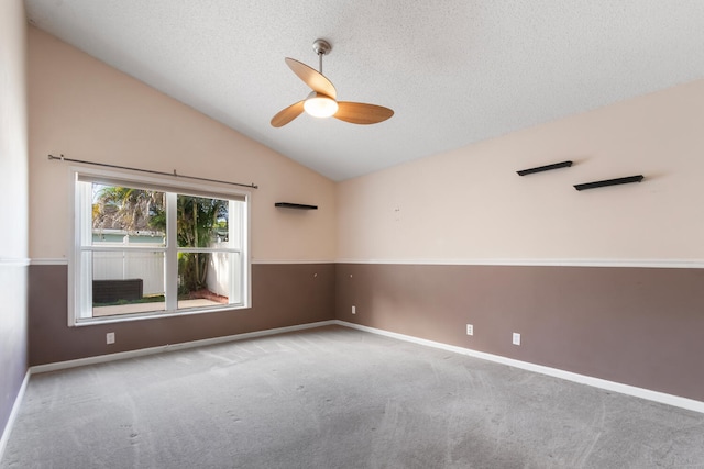 carpeted empty room with a textured ceiling, ceiling fan, and lofted ceiling