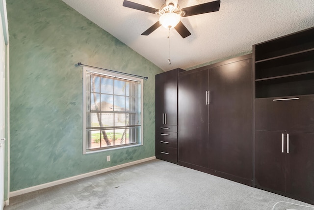 unfurnished bedroom with a textured ceiling, ceiling fan, light colored carpet, and vaulted ceiling