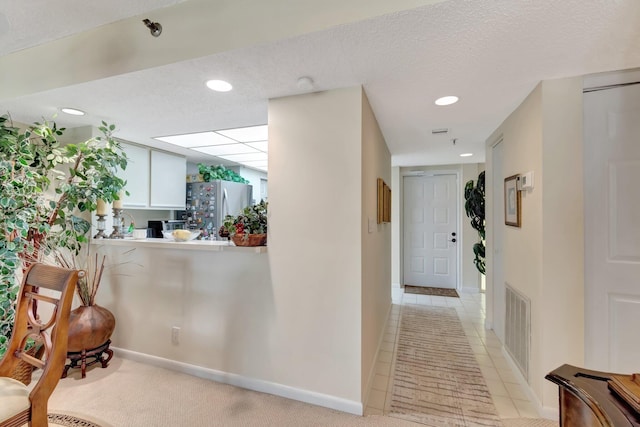 hall with light tile patterned floors and a textured ceiling