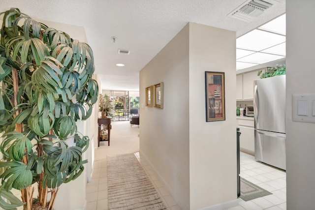 hallway with light tile patterned floors and a textured ceiling