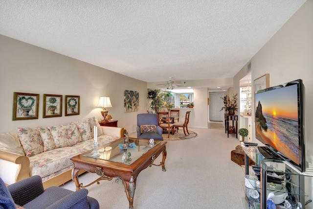 living room featuring light carpet, ceiling fan, and a textured ceiling