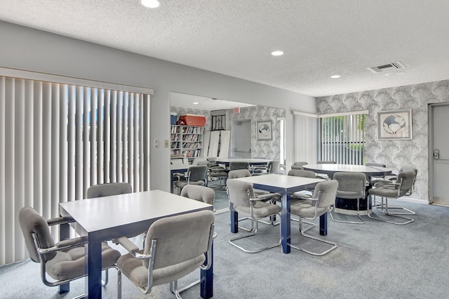 carpeted dining area with a textured ceiling