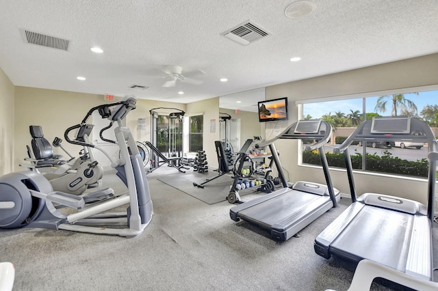 exercise room with ceiling fan and a textured ceiling