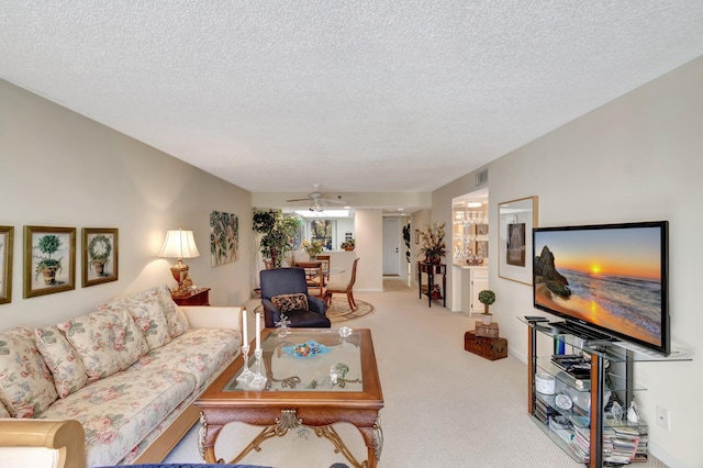 living room with light carpet, a textured ceiling, and ceiling fan