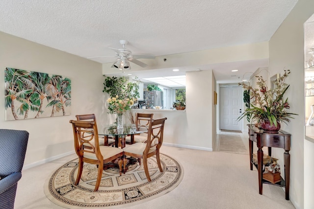 carpeted dining room with ceiling fan and a textured ceiling