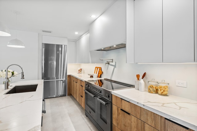 kitchen featuring light stone counters, hanging light fixtures, white cabinets, and stainless steel appliances