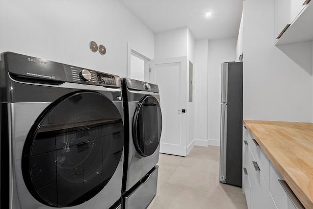 washroom with washing machine and clothes dryer and cabinets