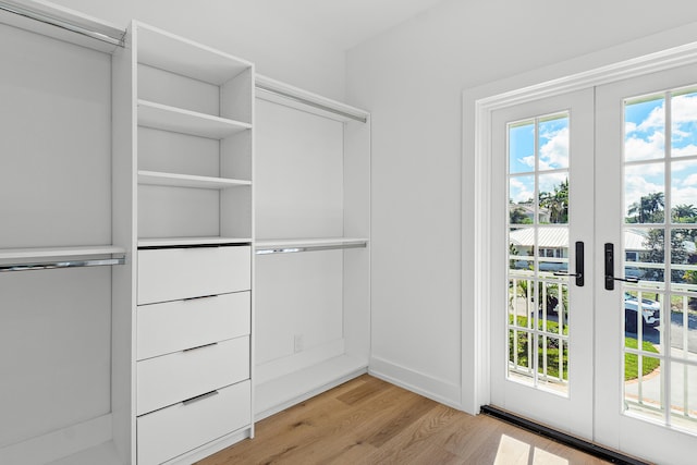 walk in closet with light hardwood / wood-style flooring and french doors