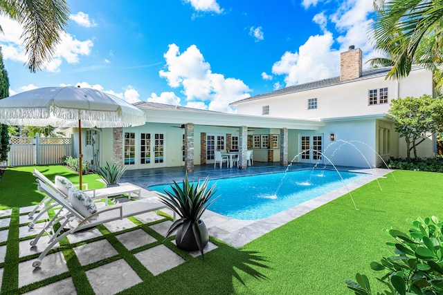 view of swimming pool featuring pool water feature, ceiling fan, a lawn, and french doors