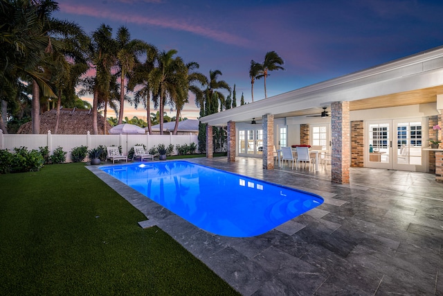 pool at dusk with ceiling fan, a patio area, and french doors