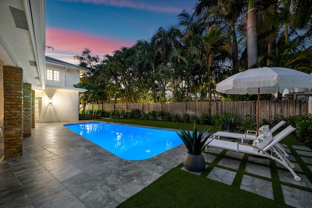 pool at dusk with a patio area