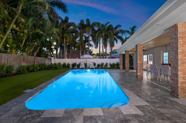 pool at dusk with a yard and a patio