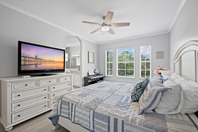 bedroom with ceiling fan, crown molding, ensuite bathroom, light hardwood / wood-style floors, and a textured ceiling