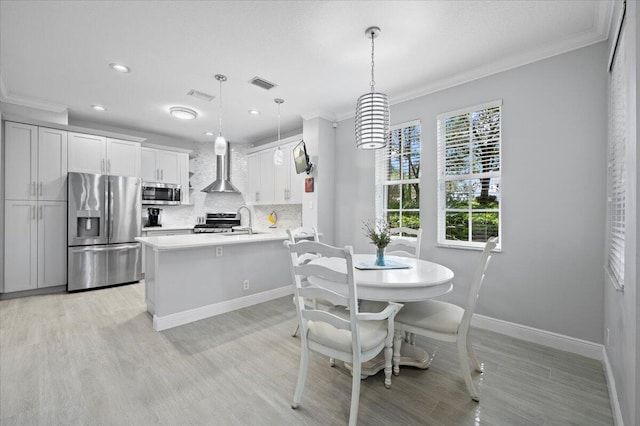 kitchen with decorative backsplash, wall chimney exhaust hood, stainless steel appliances, pendant lighting, and white cabinetry