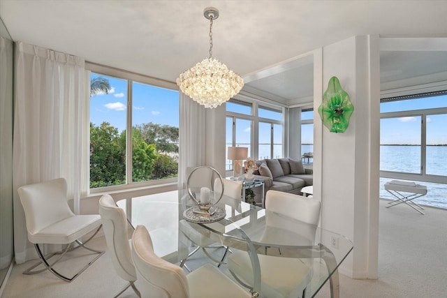 carpeted dining space featuring a water view, an inviting chandelier, and plenty of natural light