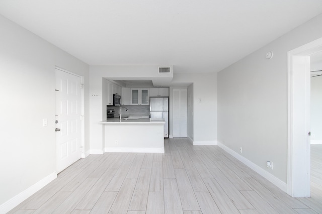 unfurnished living room featuring sink and light hardwood / wood-style floors