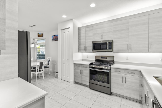 kitchen featuring gray cabinetry, light tile patterned flooring, hanging light fixtures, and appliances with stainless steel finishes