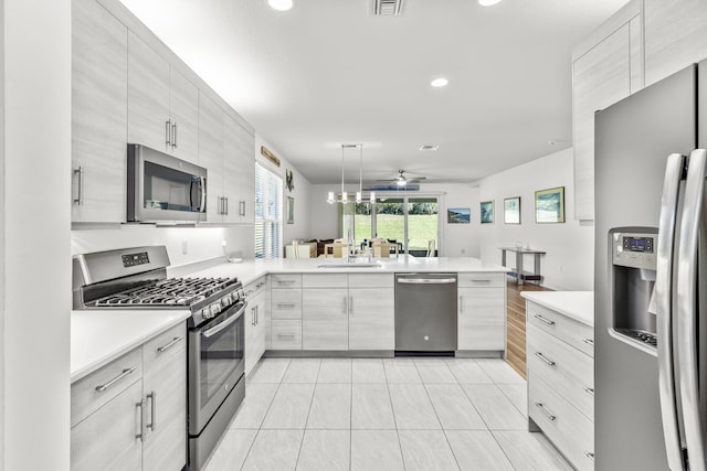 kitchen with kitchen peninsula, stainless steel appliances, ceiling fan, sink, and pendant lighting